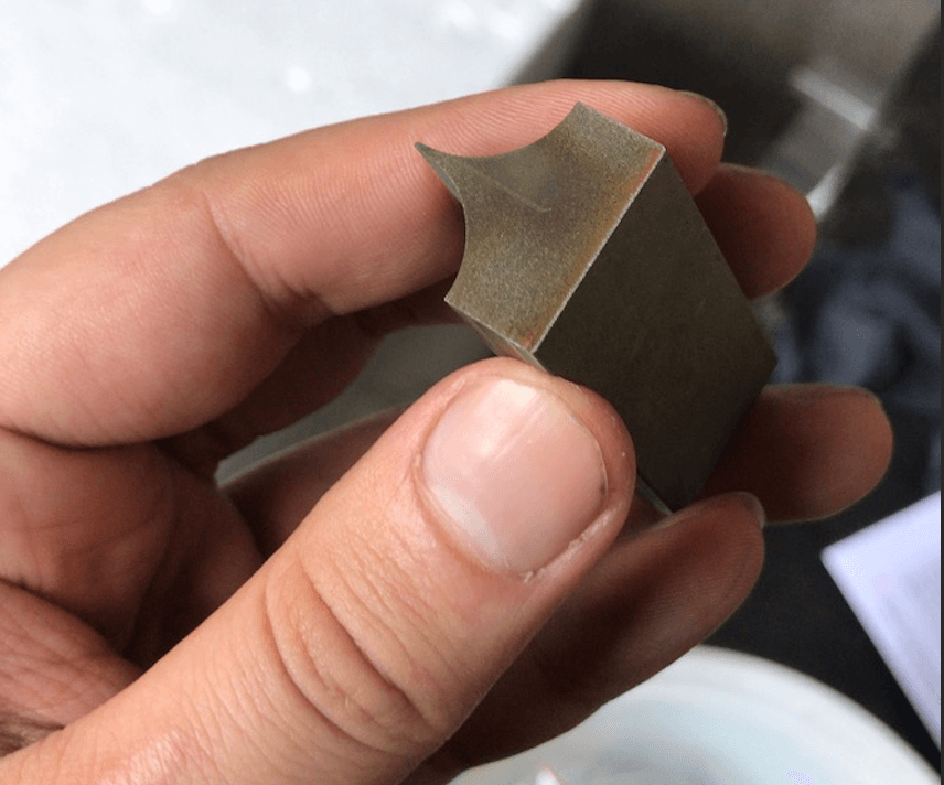 Manufactured cutting blade in hand showing precision-machined finish and final geometry